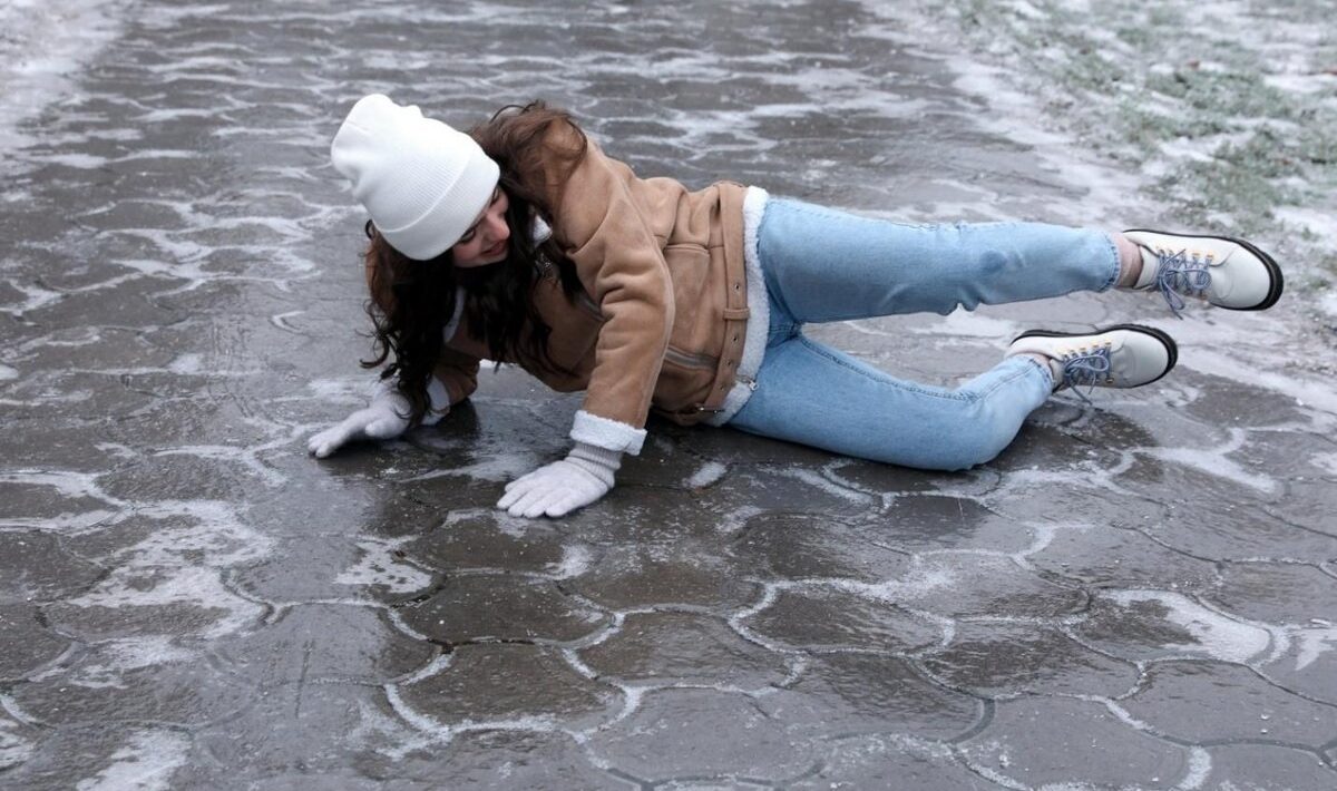 Het meisje gleed uit op het gladde trottoir